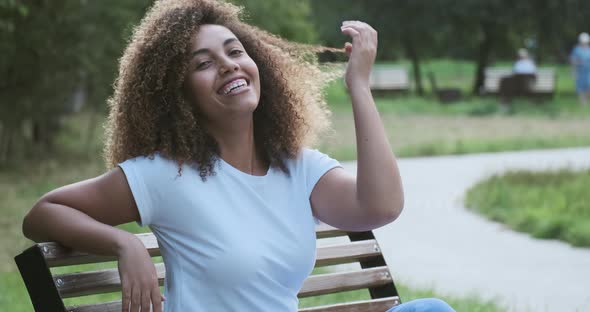 Portrait of Casual Young Smiling African American Female Relaxing Posing on Summer Park Bench