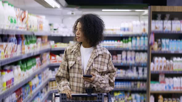 African American Lady Checking Grocery List on Smartphone at Supermarket