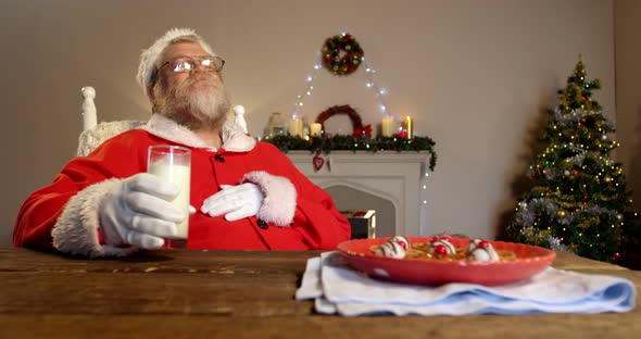 Santa claus relaxing on chair and having sweet food 4k