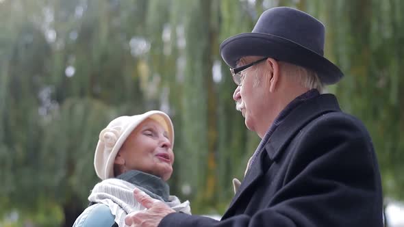 Old European man and woman dancing together in park standing. Healthy lifestyle concept.