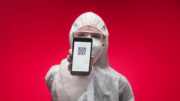 Woman Doctor Wearing Protective Uniform Showing on Phone Vaccination Passport with Qr Code