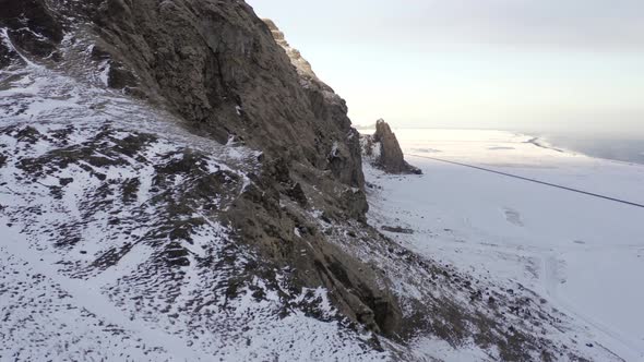 Flying Past a Snowy Rugged Mountain with Nesting Birds