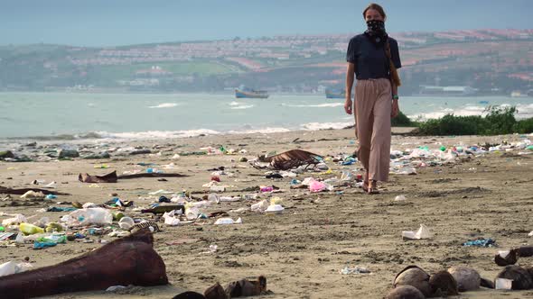 Woman Wearing Mask Walking On The Beach With Garbage And Coconut Shells. - wide shot