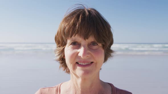 Caucasian woman looking at camera and smiling on the beach and blue sky background