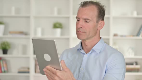 Portrait of Serious Middle Aged Businessman Using Tablet