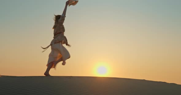 Happy Excited Woman Running By Sand Dune with Golden Sunset on Background, 