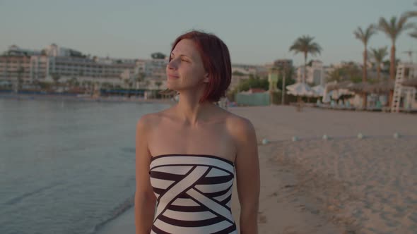 30s Woman in Swimsuit Walking on Sea Shore and Watching Beautiful Sunrise Over the Sea