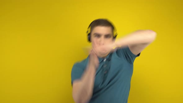 Young Man Dancing with Headphones on a Yellow Background. A Man in a Green Polo Is Listening To