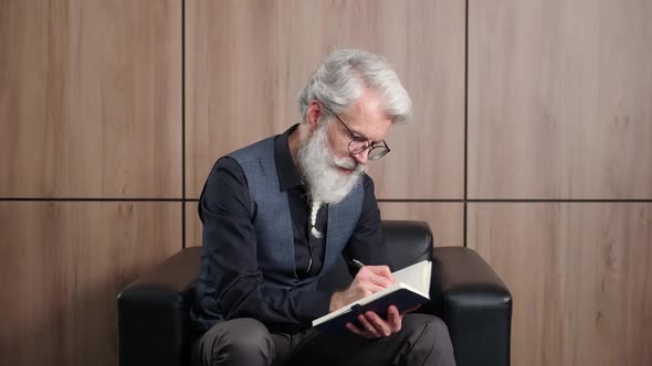 Elegant Grayhaired Man Designer Works in the Office Art Director Writes Down Ideas and Concepts in a
