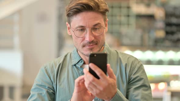 Portrait of Attractive Middle Aged Man Using Smartphone