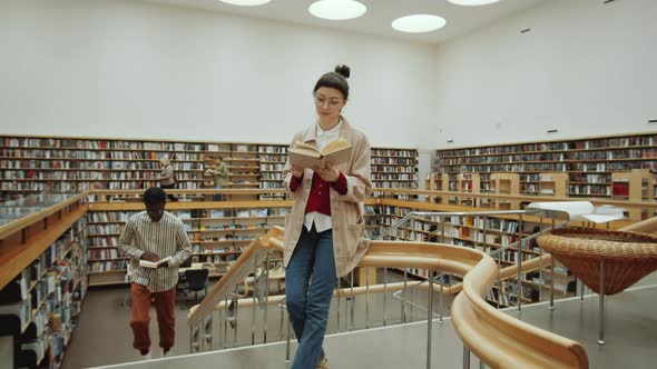 Woman Standing in Library and Reading Book