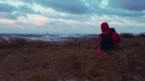 Photographer Sitting in the Field Taking Photos of the Stormy Sea