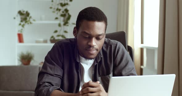 Serious African American Black Man Looking at Laptop Screen with Pensive Expression on His Face