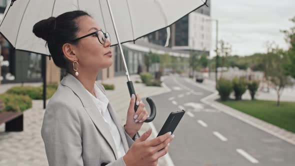 Elegant Businesswoman with Umbrella Using Mobile Phone