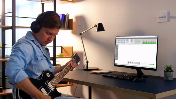 Man Playing Guitar and Recording Music at Home