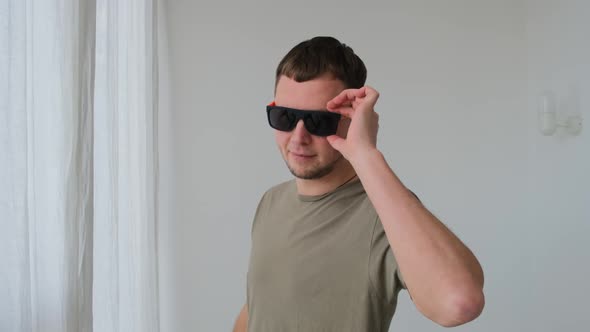 Cool Guy with Stylish Sunglasses Poses for Camera By Wall