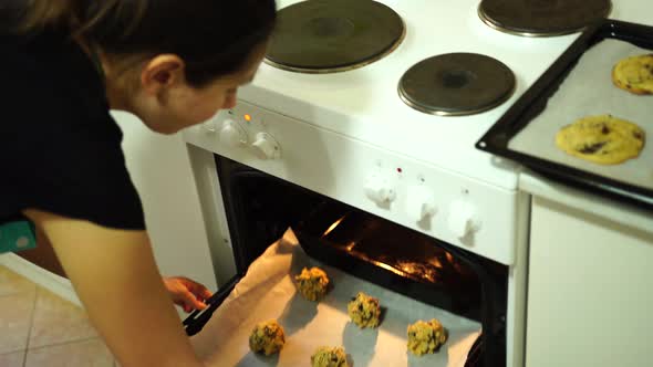Girl Puts a Baking Sheet of American Chocolate Chip Cookies in a Preheated Oven