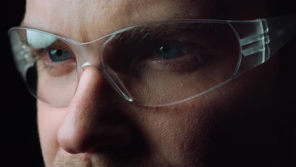 Close Up of Face of Focused Man Opening Beautiful Blue Eyes with Glasses