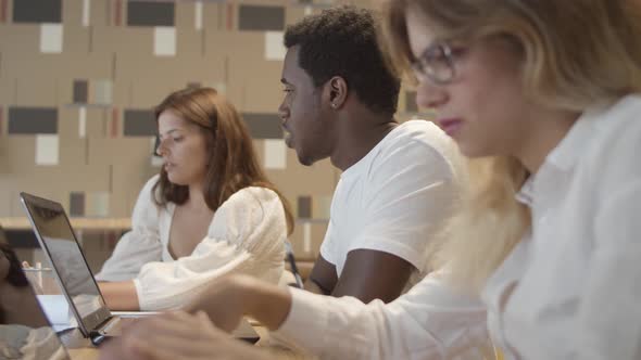 Creative Team Sitting at Table with Laptops