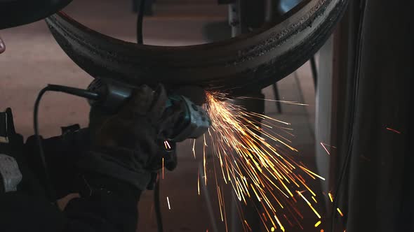 The Welder Processes the Weld with a Grinding Machine and Sparks Fly