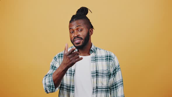 Young Dark Skinned Afro Male Smiling Pointing at you By Forefinger and Showing Loser Hand Gesture