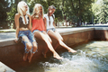 Girlfriends sitting at the fountain and dangling legs to the water - PhotoDune Item for Sale