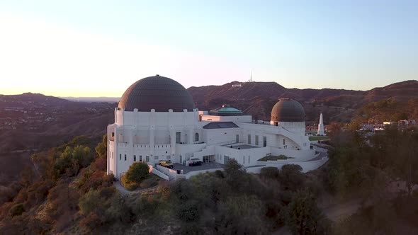 Aerial orbit of the Griffith Observatory and the iconic Hollywood sign in the distance.