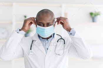 African american male therapist wearing medical surgical mask to prevent infection, working in / Photodune, Misc