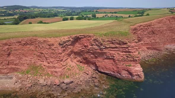 4k Aerial, rising up over oceanfront sandstone cliffs toward sprawling fields