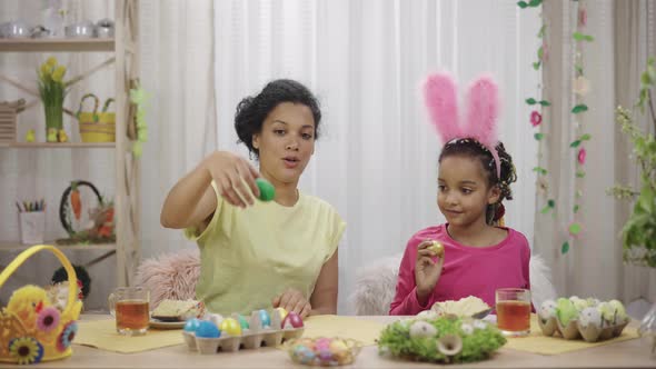 Mom and Daughter Have Fun and Break Easter Eggs