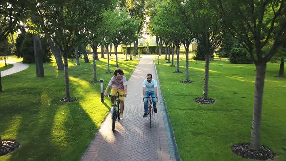 Two Man Cycling Through Park