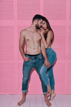 ful young couple embracing while standing against pink background