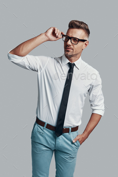 g away and adjusting his eyewear while standing against grey background