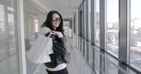 Rear View of Woman with Bags Walking in Shopping Center