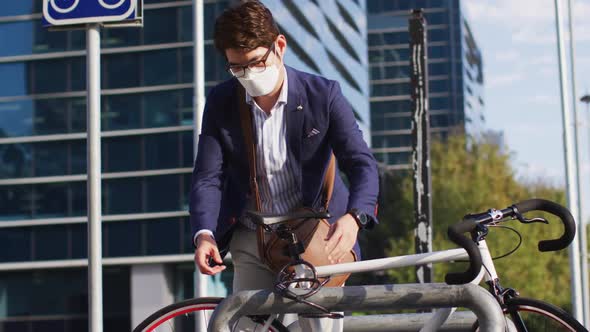 Asian man wearing face mask locking his bicycle at corporate park