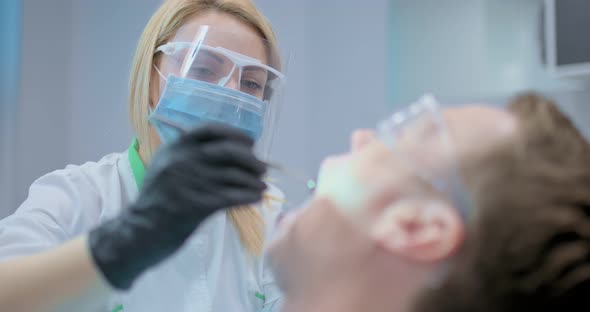 Young Female Dentist Examines an Oral Cavity in a Patient Using Dental Tools