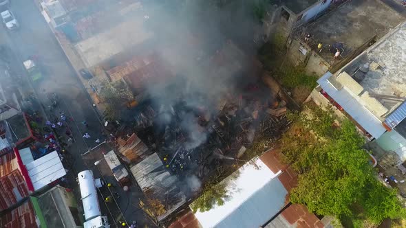 Aerial view of firemen calming a building on fire, in middle of the city - circling, drone shot