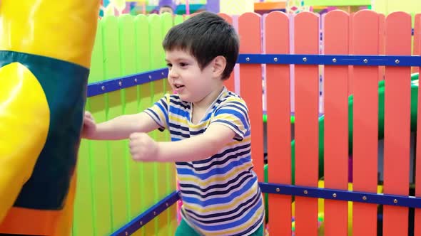 A Preschool Boy of 4 Years Old Plays with a Punching Bag for Boxing in the Playroom