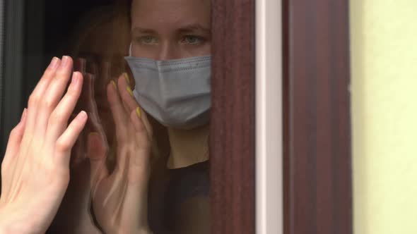 Two girls, sisters touch their hands with their palms through a glass window,