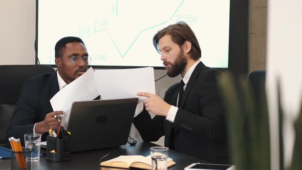 Two Businessmen in Suits Having a Discussion at Office