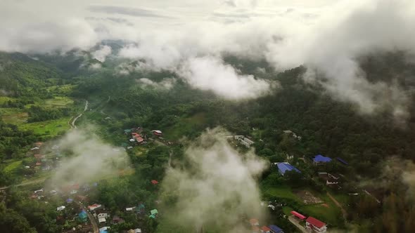 Aerial view flying above lush green tropical rain forest mountain with rain cloud cover during the r