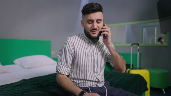 Young Bearded Confident Man Talking on the Phone After Arrival in Hotel