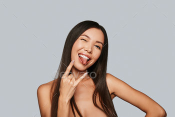 uring and sticking out tongue while standing against grey background