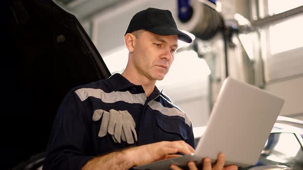 Car Mechanic Working on Laptop in Auto Repair Service Low Angle View