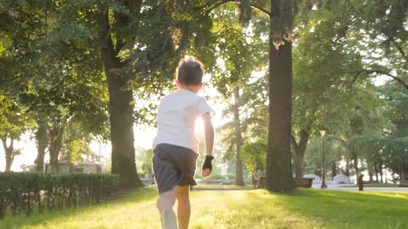 A Child in a White Shirt Running in the Park Towards the Sun, Tracking Shot