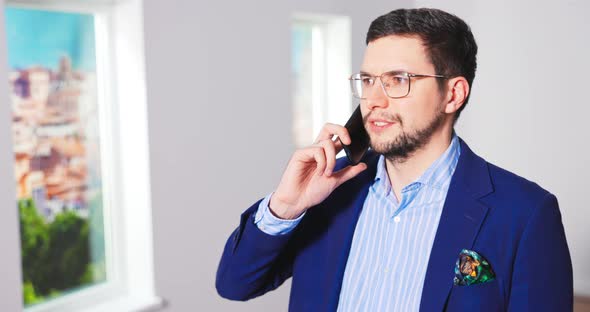 Portrait of Handsome Young Caucasian Male Real Estate Agent in Suit Standing in Empty Apartment