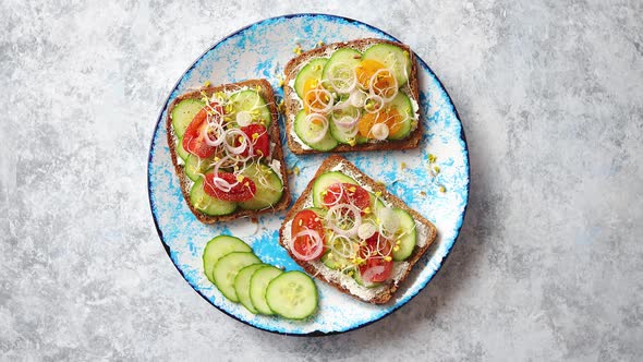 Plate with Toasts with Cucomber, Tomatoes and Crumbled Feta and Radish Sprouts