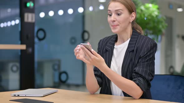 Excited Young Businesswoman Celebrating Success on Smartphone