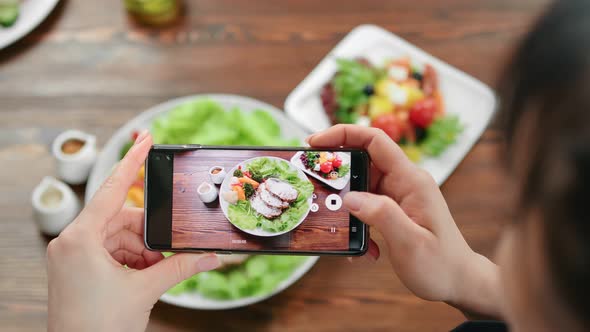 Top View Female Taking Photo of Food on Serving Plate Using Smartphone