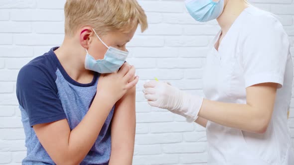 Nurse in Protective Mask Making Injection From Coronavirus for Boy